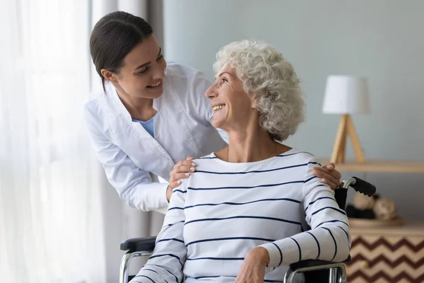 Positive nurse take care of elderly disabled woman — Stock Photo, Image