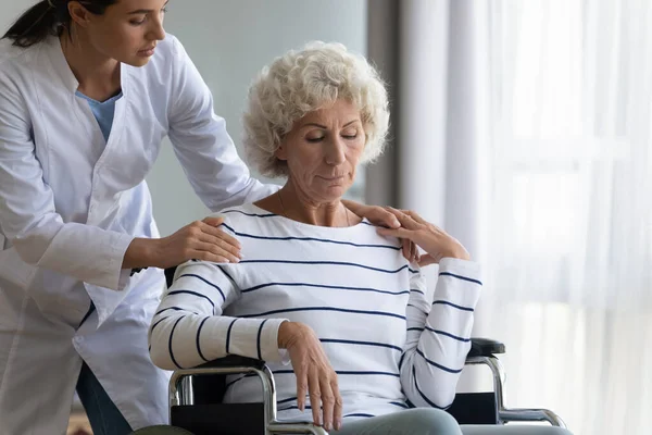 Stödjande kvinnlig sjuksköterska ta hand om funktionshindrade äldre kvinna — Stockfoto