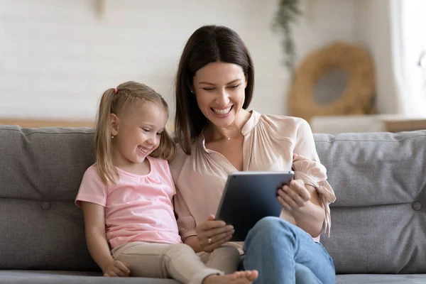 Happy mom and daughter playing on tablet together