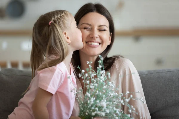 Little girl kiss mama prezent kwiaty pozdrowienie z urodzinami — Zdjęcie stockowe