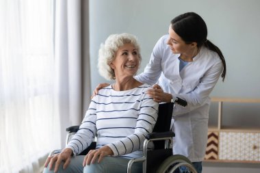 Bayan doktor engelli yaşlı bayanla ilgileniyor.