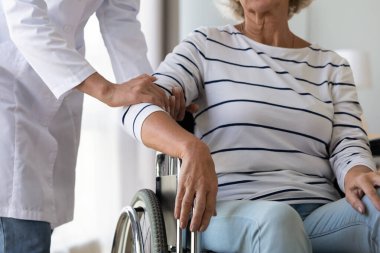 Bayan hemşire engelli kıdemli hastayla ilgileniyor.