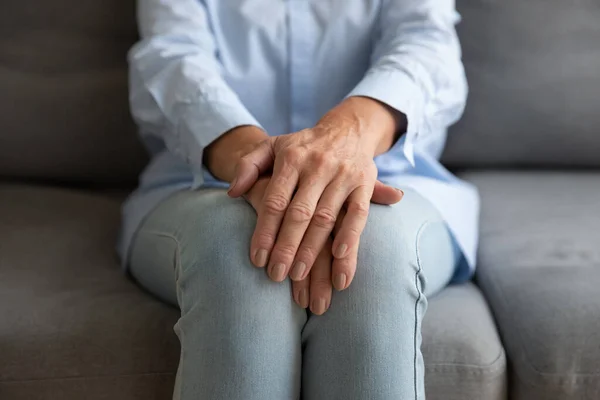 Großaufnahme einer alten Frau, die mit gefalteten Händen sitzt — Stockfoto