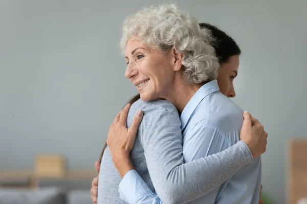 Happy elderly mom and grown-up daughter hug embrace make peace after fight — Stock Photo, Image