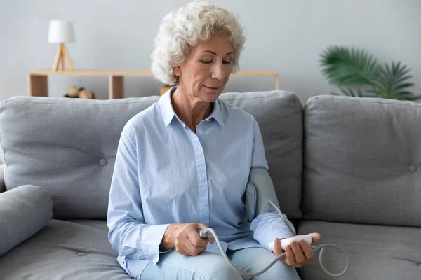 Mature woman check blood pressure on tonometer