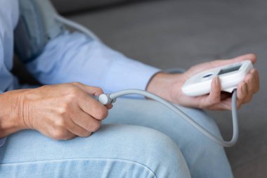 Yaşlı kadın hasta evde elektronik tonometre kullanıyor.