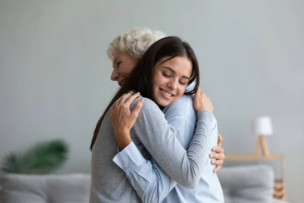 Щаслива старша мати і доросла дочка обіймаються вдома — стокове фото