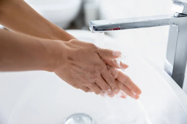 Closeup view woman cleans hands under running water from tap — Stock Photo, Image