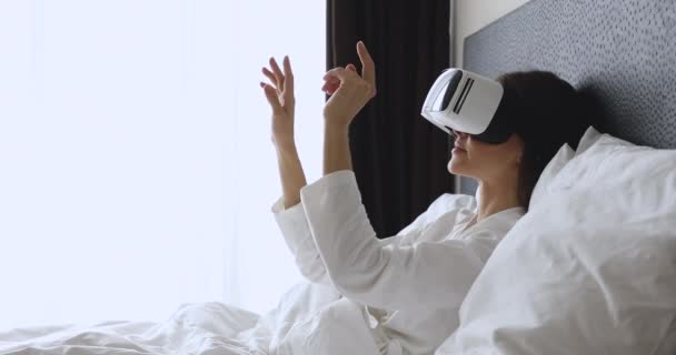 Jonge vrouw met virtual reality bril, in bed blijven. — Stockvideo