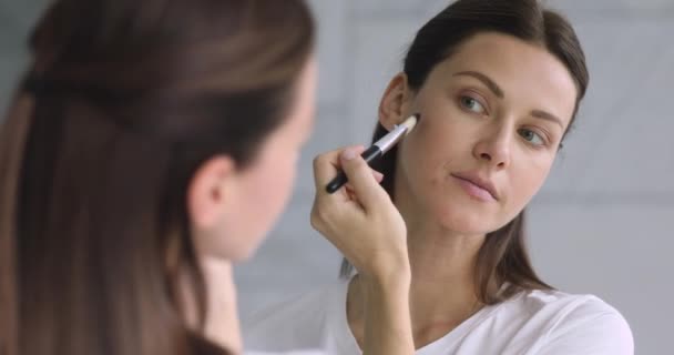 Reflejo espejo atractiva joven morena haciendo maquillaje . — Vídeo de stock