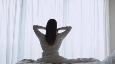 İpek gecelikli esmer kadın kol kaslarını esnetiyor..