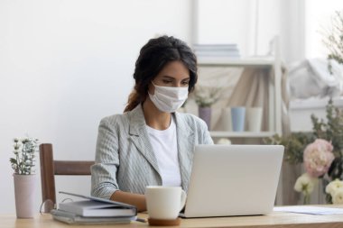 Ofiste çalışan tıbbi maskeli kadın çalışan.