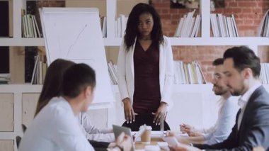 Ciddi bir Afrikalı kadın yönetici toplantıda çalışan grupla konuşur.