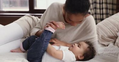 Afrikalı anne yatakta küçük şirin bir bebekle öpüşüyor.
