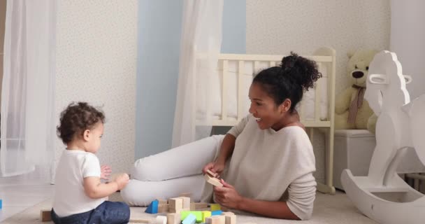 Младенец дочь играет деревянные блоки сидя на полу с мамой — стоковое видео