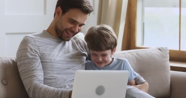 Счастливый смеющийся маленький ребенок играет в игру с отцом на компьютере . — стоковое видео