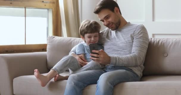 Feliz pai dedicado jogar jogos móveis com o filho . — Vídeo de Stock