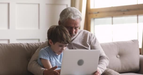 Lächelnder kleiner Sohn schaut Film mit Großvater zu Hause. — Stockvideo