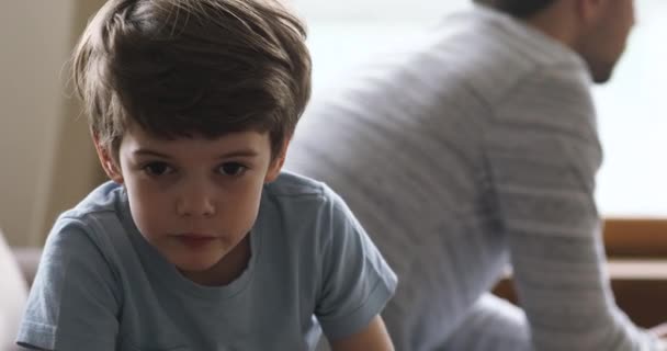 Smutný chlapec sedí na gauči odděleně od naštvaného otce. — Stock video
