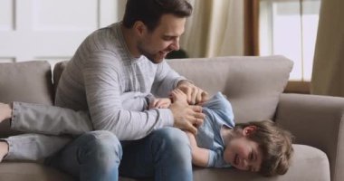 Sevecen genç baba, gülen küçük çocuğu gıdıklıyor..
