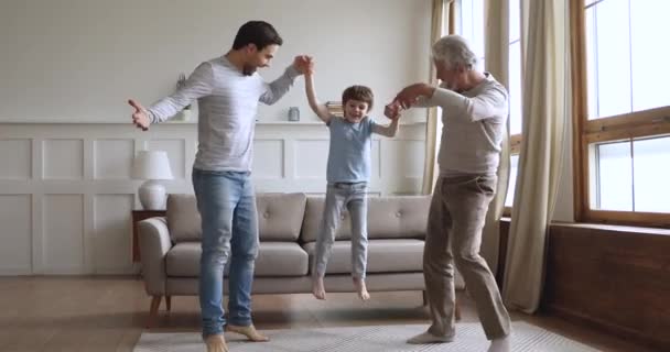 Överlycklig liten pojke hoppar med pappa och farfar. — Stockvideo