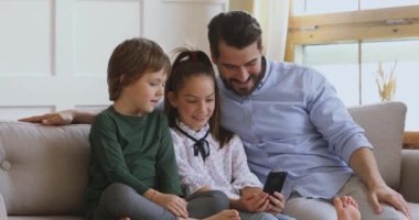 Küçük kız, küçük kardeş ve babaya komik karikatürler gösteriyor..