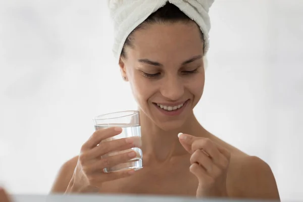 Woman holding pill and glass of water smiling feels healthy — Stock Photo, Image