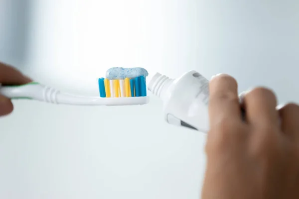 Close up image female hands squeezes toothpaste on toothbrush — Stock Photo, Image