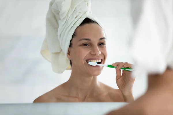 After shower woman looking in mirror and brushing her teeth — Stock Photo, Image