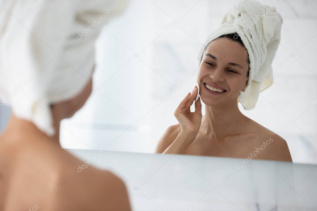 Woman cleanses skin using cotton pad and cosmetics products