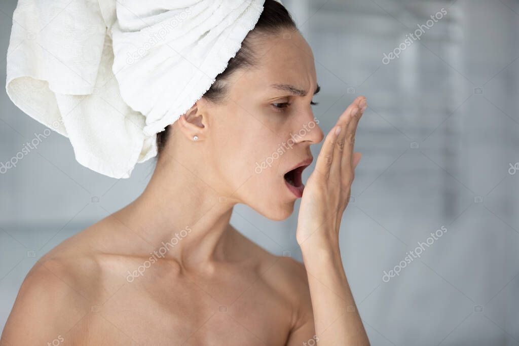 Woman with towel on head opens mouth check breath