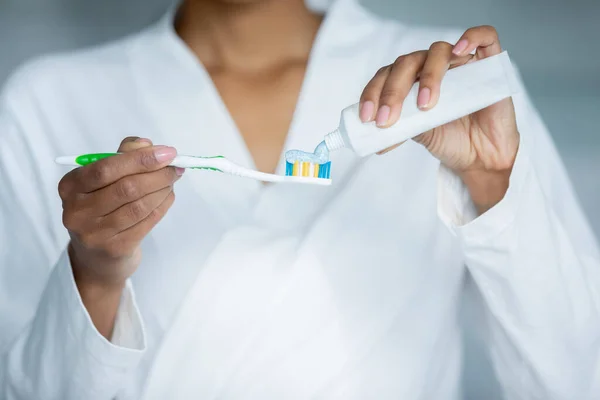 Closeup view female hands apply toothpaste from tube at toothbrush — Stock Photo, Image