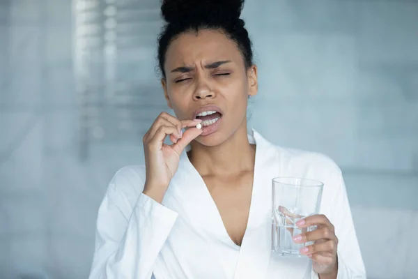 Ungesunde Afrikanerin mit Glas Wasser nimmt Schmerzmittel — Stockfoto