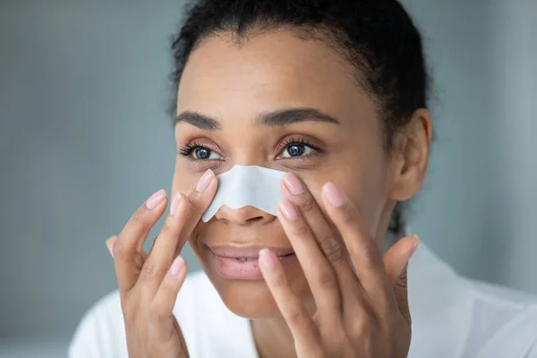 Cerca de la cara de la mujer africana aplicando limpieza de la tira nasal — Foto de Stock