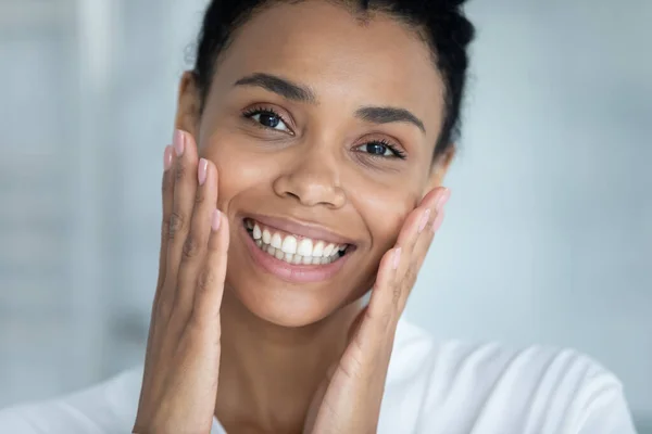 Afrikansk kvinna kontrollera ansiktet efter skönhetsbehandling känns nöjd närbild — Stockfoto