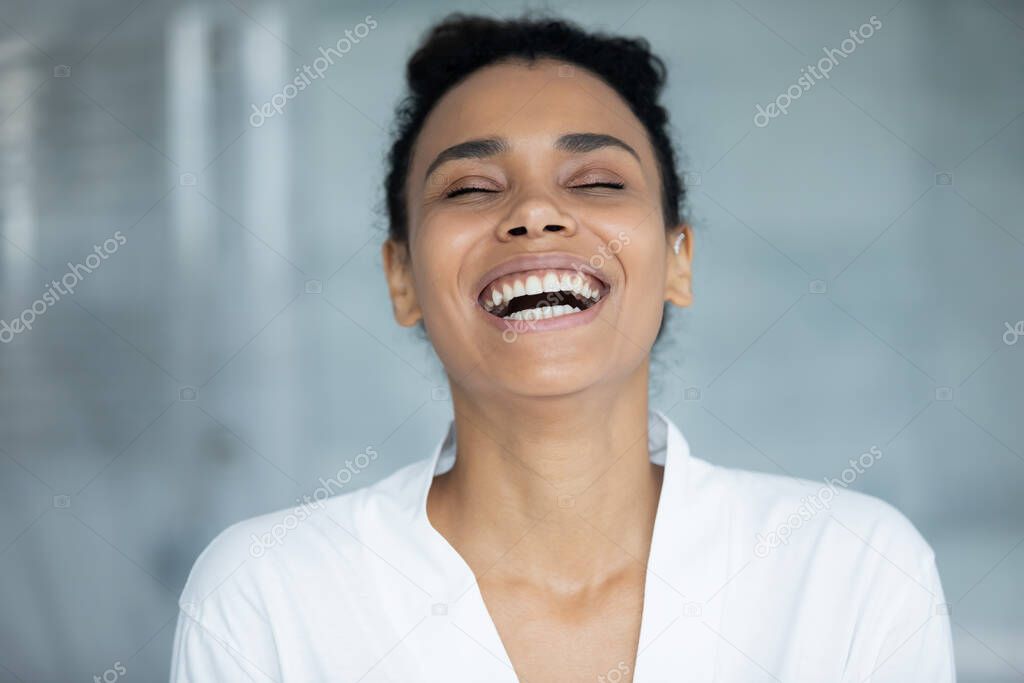 African cheerful woman in white bathrobe laughing standing in bathroom