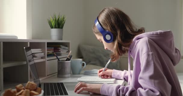 Adolescente usando fones de ouvido estudando on-line de casa — Vídeo de Stock