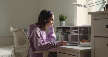 Kulaklık takan genç kız evdeki laptoptan arıyor.