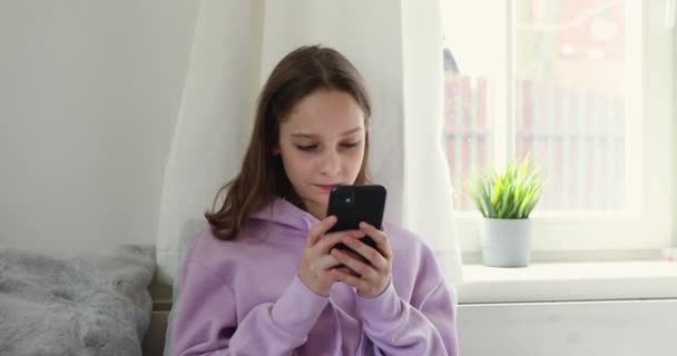 Teenage girl holds smartphone using mobile app at home — Stock Video