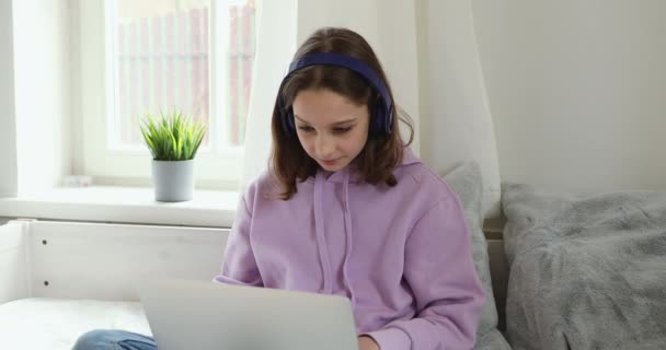 Adolescente portant des écouteurs regarder cours vidéo éducatif à l'aide d'un ordinateur portable — Video