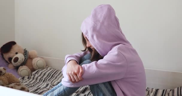 Depressief tiener meisje dragen kap zitten op bed alleen — Stockvideo