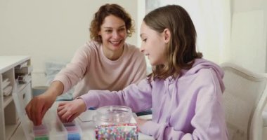 Ergen kız ve anne evdeki masada mozaik oyunu oynuyorlar.