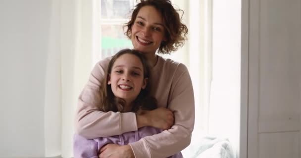 Boldog szeretetteljes fiatal anya ölelés tini lánya nézi kamera — Stock videók