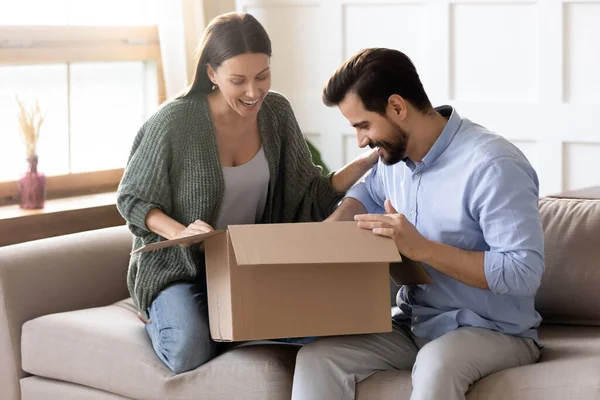 Joyeux jeune couple marié déballage boîte en carton à la maison . — Photo