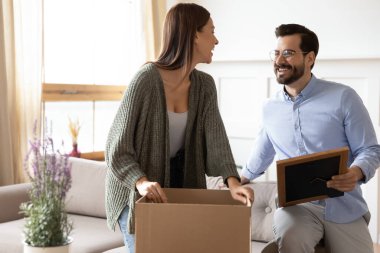 Karton kutulardan eşyaları boşaltan neşeli evli bir çift..