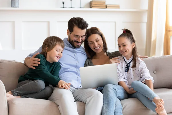 笑顔の両親は小さな子供を抱っこしてノートパソコンの画面を見て. — ストック写真
