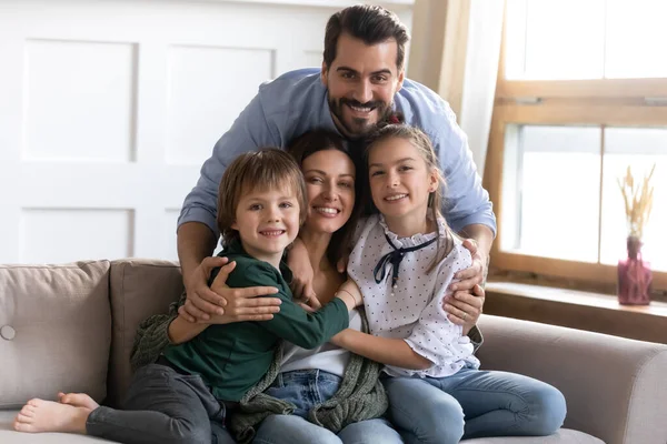 Liebevoll lächelnde Familie posiert für Foto im Wohnzimmer. — Stockfoto