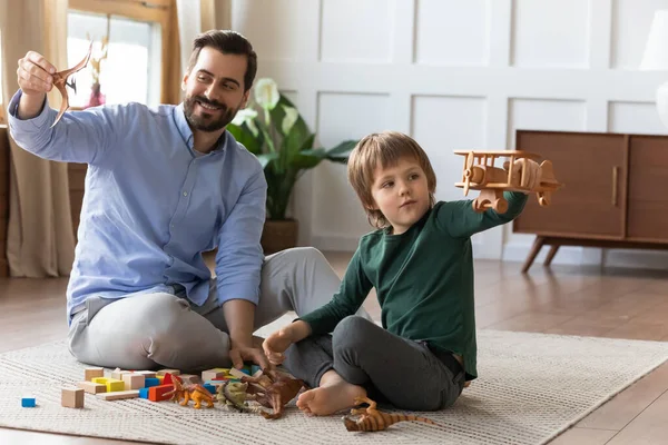 Kleiner Junge spielt mit Holzflugzeug und genießt die Zeit mit Papa. — Stockfoto