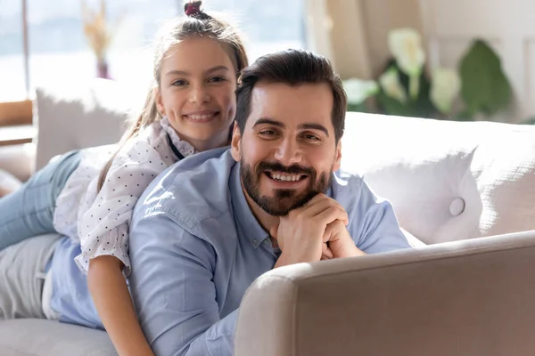 Porträt eines glücklichen kleinen schulpflichtigen Mädchens, das auf dem Rücken des Vaters liegt. — Stockfoto