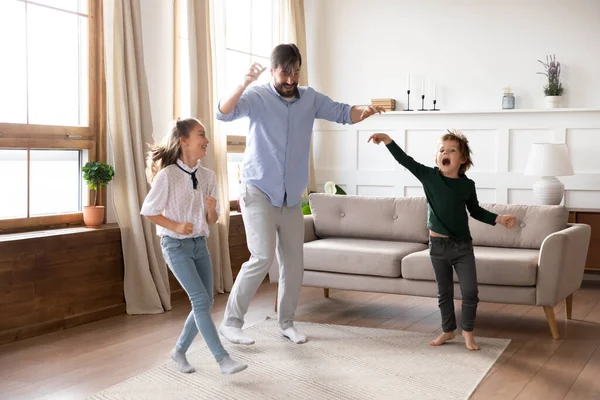 Pai animado desfrutando de atividade engraçada com crianças na sala de estar . — Fotografia de Stock